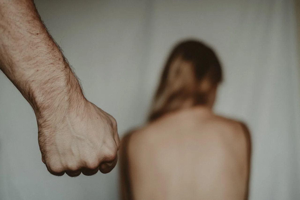 Fist raised in aggression with a blurred figure in the background, symbolizing violence and potential assault, relevant to criminal defense law topics such as aggravated assault and sexual assault.