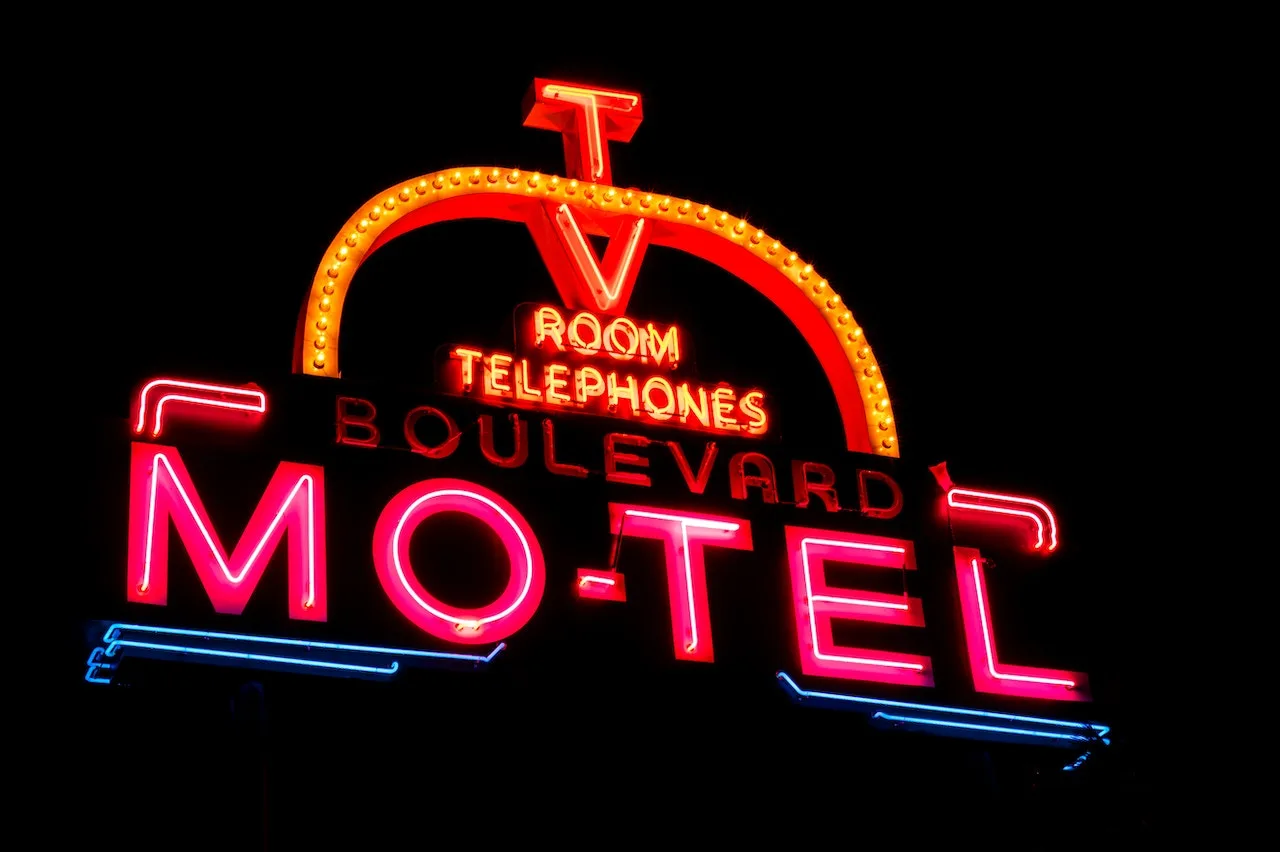 David Smith Law Firm, PLLC 116 Neon sign for Boulevard Motel featuring "TV," "Room," and "Telephones," illuminated against a dark background, representing potential accommodations relevant to criminal defense consultations.