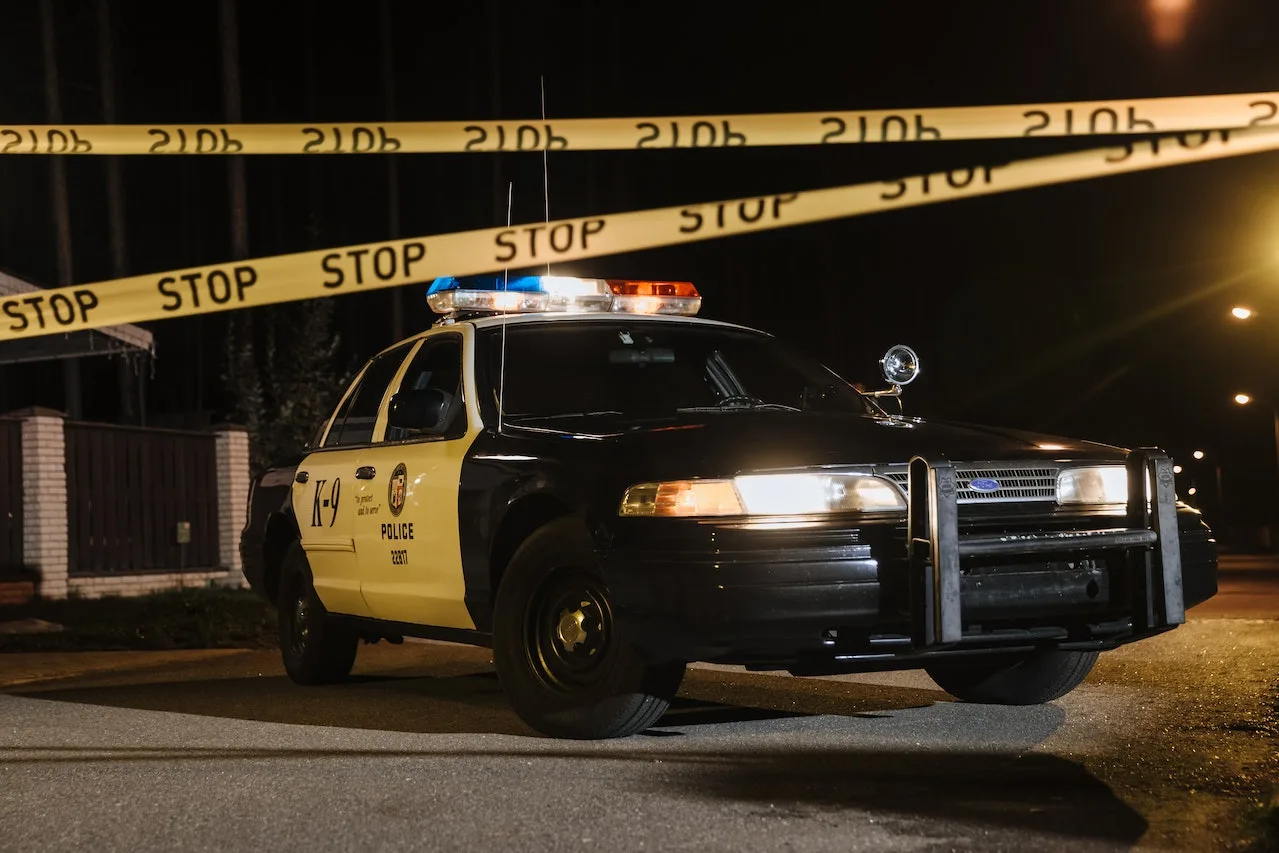 pexels-cottonbro-studio-10466472 Police car with flashing lights parked near crime scene tape, symbolizing criminal law enforcement and legal issues relevant to David Smith Law Firm's practice areas.