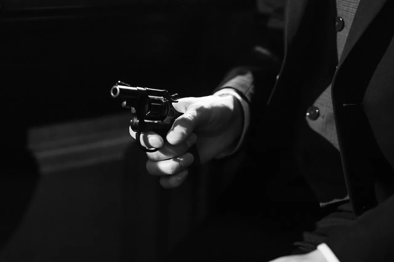 pexels-cottonbro-studio-7265995 Hand holding a revolver, dressed in a suit, symbolizing criminal offenses related to weapons, relevant to the law firm's focus on serious criminal charges.