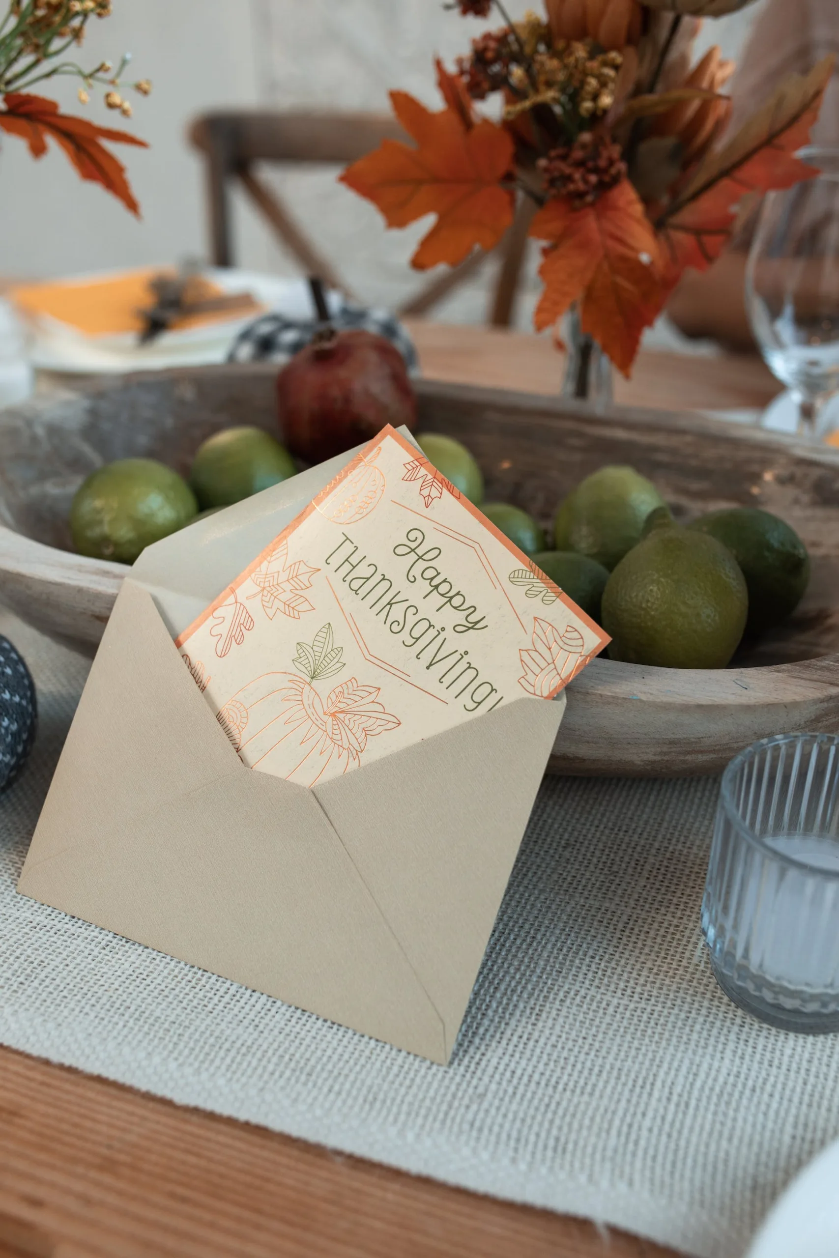 Thanksgiving card in envelope with autumn leaves and decorative pumpkins, surrounded by fresh limes and an apple, reflecting gratitude and seasonal celebration at David Smith Law Firm, PLLC.