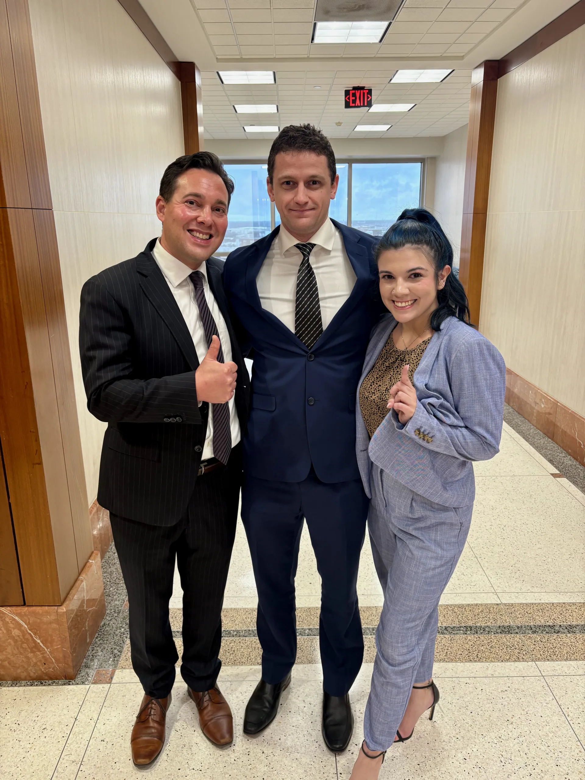 Victory in Court: In-Trial Dismissal of a DWI Case. David Smith and Savanna Luna in court attire on either side of our client outside the courtroom after the in-trial dismissal.
