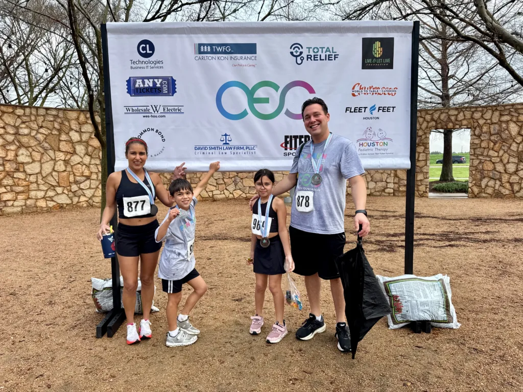 David Neha Liana Shaan istanding n front of sponsors banner after race