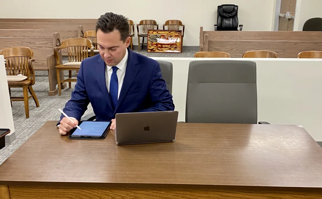 A man in a suit sitting at a desk with a laptop