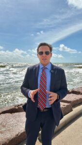 New Homepage - Frontpage 18 David Smith wearing a suit and tie standing next to the Gulf of Mexico in Galveston.